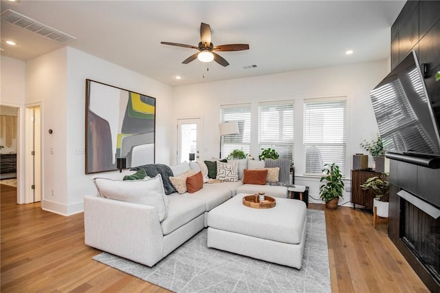 living area featuring ceiling fan, light wood-type flooring, recessed lighting, a fireplace, and baseboards