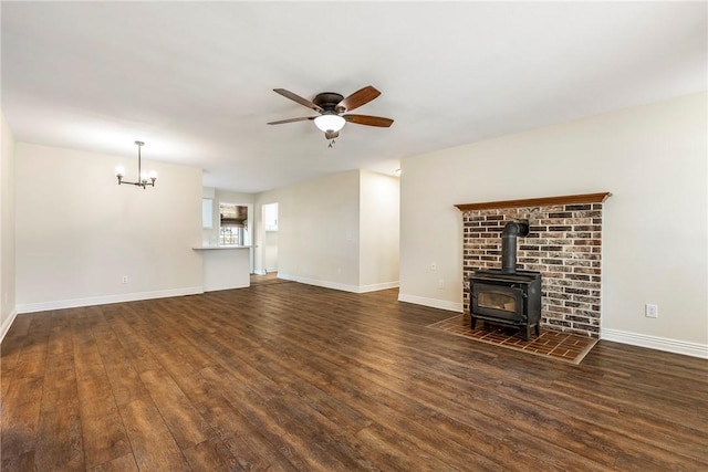 655 Bloomfield St, Gentry, AR 72734 - unfurnished living room featuring a wood stove, wood finished floors, a ceiling fan, a chandelier, and baseboards