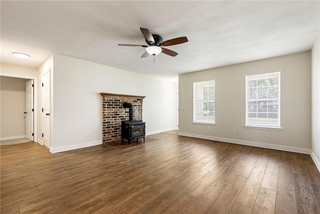 655 Bloomfield St, Gentry, AR 72734 - unfurnished living room featuring a wood stove, wood finished floors, a ceiling fan, and baseboards