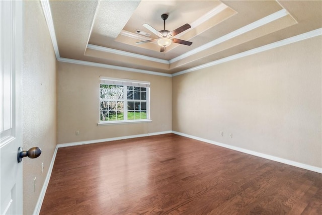 unfurnished room with a tray ceiling, a ceiling fan, wood finished floors, ornamental molding, and baseboards