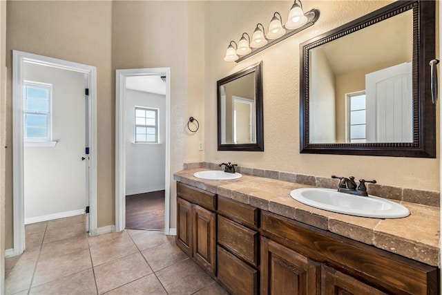 bathroom featuring tile patterned floors, baseboards, and double vanity