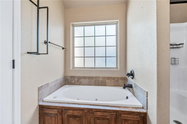 full bathroom featuring a whirlpool tub, a textured wall, and a shower