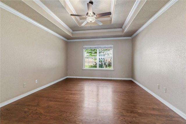 empty room with a tray ceiling, wood finished floors, ceiling fan, ornamental molding, and baseboards