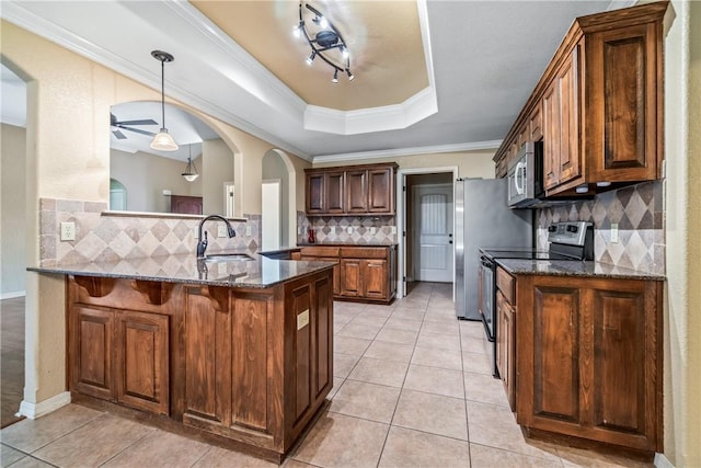 kitchen featuring appliances with stainless steel finishes, a sink, a kitchen bar, backsplash, and arched walkways