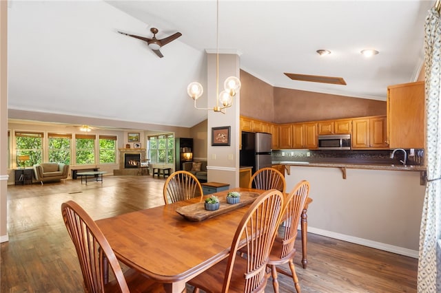 10 Forfar Cir, Bella Vista, AR 72715 - dining area featuring ceiling fan, a warm lit fireplace, high vaulted ceiling, wood finished floors, and baseboards