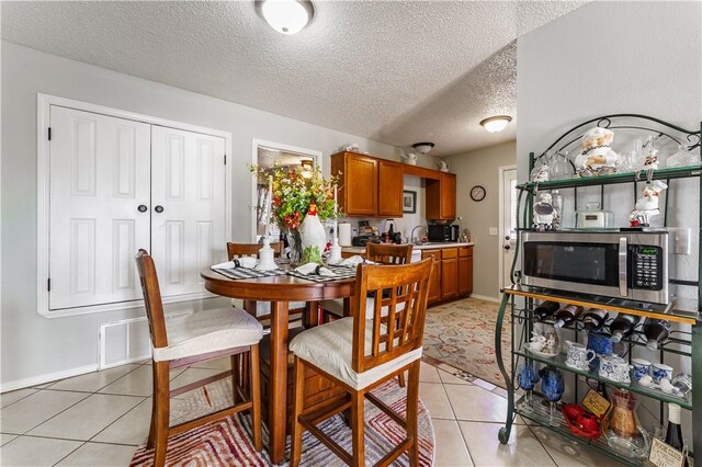 dining space featuring light tile patterned floors, a textured ceiling, and baseboards