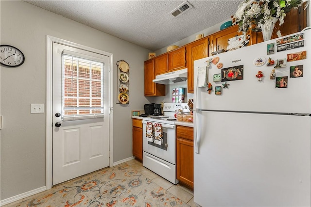 kitchen with white appliances, under cabinet range hood, brown cabinets, light countertops, and a textured ceiling