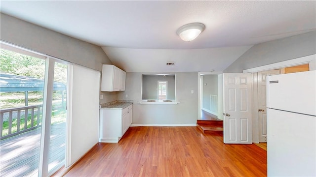 1230 W Mount Comfort Rd, Fayetteville, AR 72703 - kitchen with freestanding refrigerator, vaulted ceiling, plenty of natural light, white cabinets, and light wood-type flooring