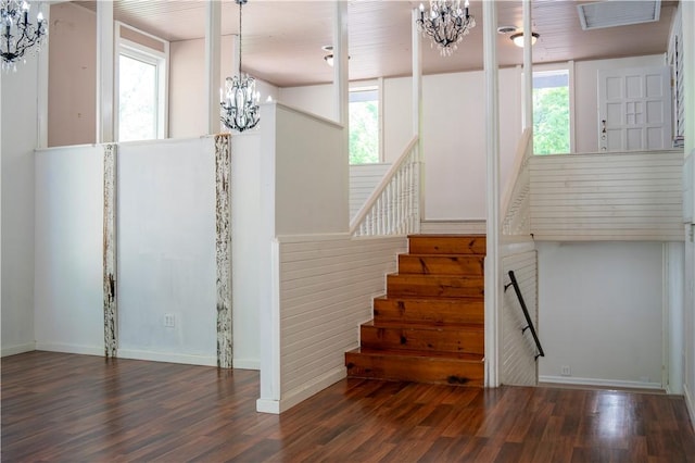 staircase featuring a chandelier, wood finished floors, and healthy amount of natural light