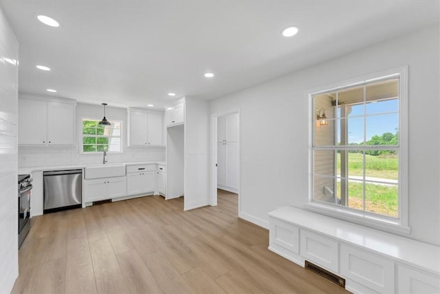 12391 Shamrock Rd, Farmington, AR 72730 - kitchen with stainless steel dishwasher, a sink, stove, white cabinetry, and backsplash