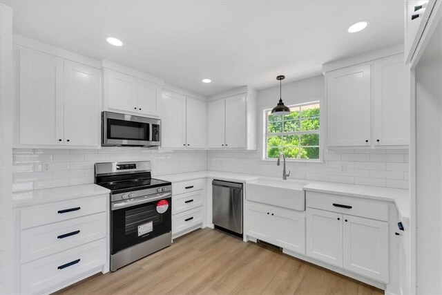 12391 Shamrock Rd, Farmington, AR 72730 - kitchen featuring stainless steel appliances, a sink, white cabinetry, backsplash, and light wood-type flooring