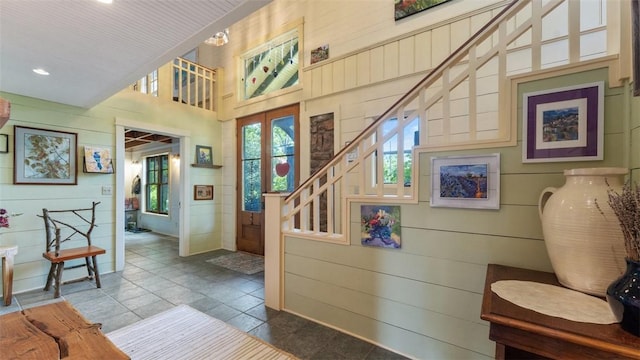 entrance foyer with wooden walls, high vaulted ceiling, recessed lighting, and stairs