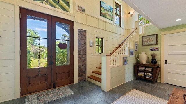 foyer featuring french doors, stairway, plenty of natural light, wooden walls, and recessed lighting