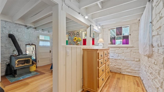 bathroom with beam ceiling, wood-type flooring, and a wood stove