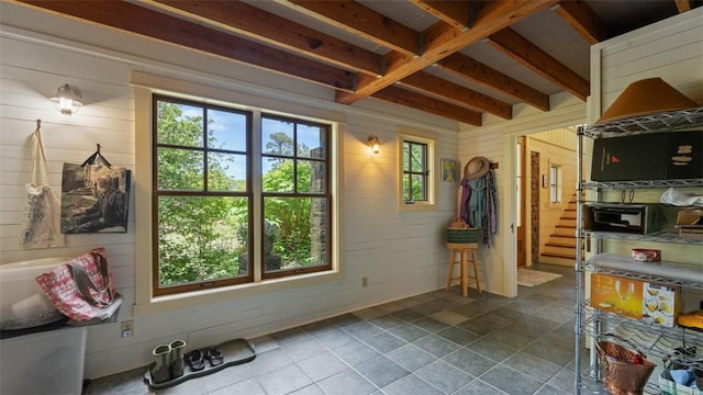 living area with wooden walls, stairway, and beamed ceiling