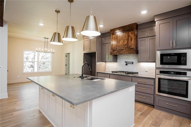 25 Lathrop Dr, Bella Vista, AR 72715 - kitchen with appliances with stainless steel finishes, a sink, light wood-type flooring, tasteful backsplash, and an island with sink