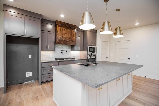 25 Lathrop Dr, Bella Vista, AR 72715 - kitchen featuring a sink, light wood-type flooring, a kitchen island with sink, stainless steel appliances, and decorative backsplash