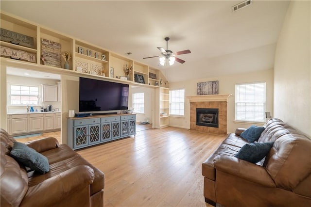 living room with ceiling fan, light wood-style flooring, lofted ceiling, and a fireplace