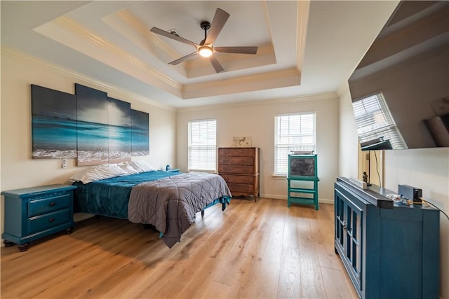 bedroom featuring a raised ceiling, ornamental molding, multiple windows, light wood finished floors, and a ceiling fan