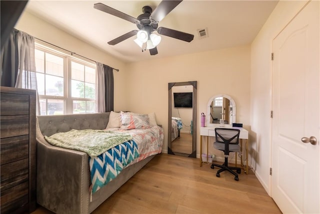 bedroom with wood finished floors, multiple windows, baseboards, and a ceiling fan