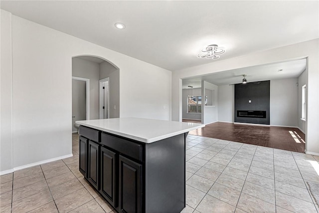 1302 Walker Dr, Rogers, AR 72756 - kitchen with light tile patterned floors, arched walkways, dark cabinetry, light countertops, and recessed lighting