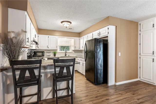 1801 Jean St, Springdale, AR 72762 - kitchen featuring black appliances, a peninsula, white cabinets, wood finished floors, and a textured ceiling