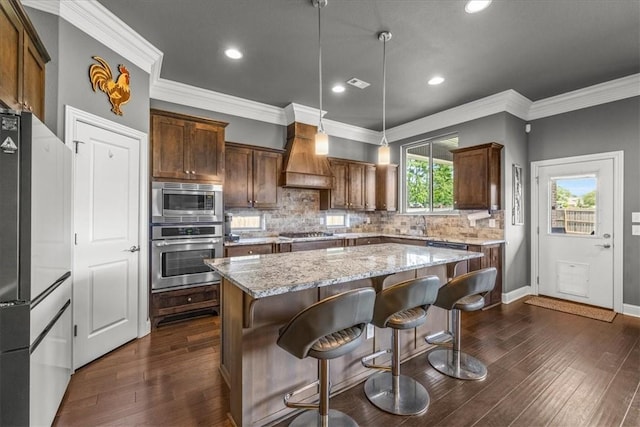 kitchen with stainless steel appliances, premium range hood, a center island, dark wood finished floors, and recessed lighting