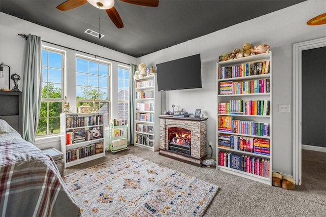 carpeted bedroom with a fireplace, multiple windows, ceiling fan, and baseboards
