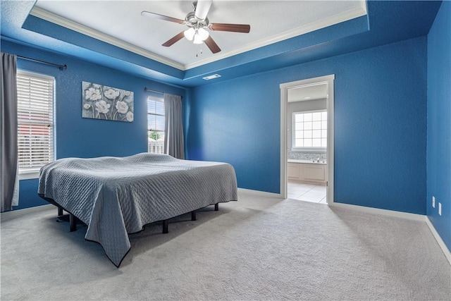 bedroom featuring crown molding, carpet floors, a tray ceiling, connected bathroom, and baseboards