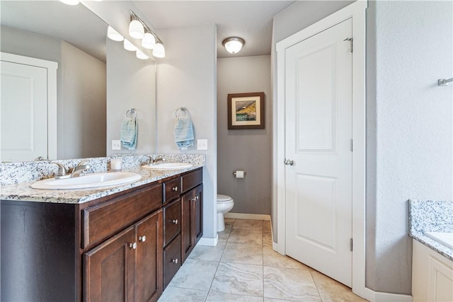 bathroom with double vanity and toilet