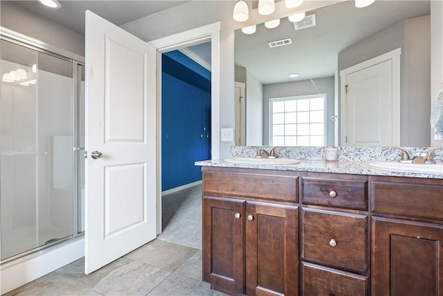 bathroom featuring a stall shower, double vanity, tile patterned flooring, and baseboards