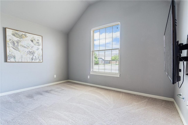 empty room with carpet floors, vaulted ceiling, and baseboards