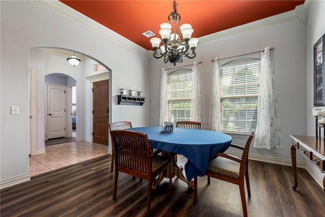 dining room with arched walkways, ornamental molding, wood finished floors, a chandelier, and baseboards