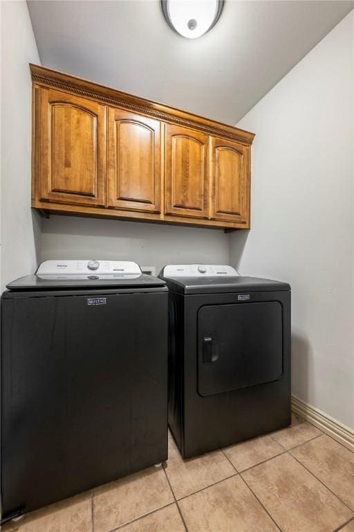 laundry room with cabinet space, independent washer and dryer, light tile patterned floors, and baseboards