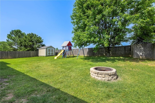 view of yard featuring a shed, a playground, a fire pit, and an outdoor structure