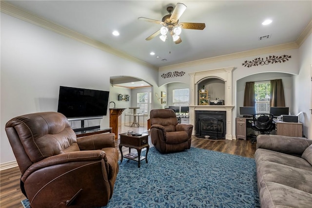 living room with crown molding, ceiling fan, arched walkways, dark wood-type flooring, and a fireplace
