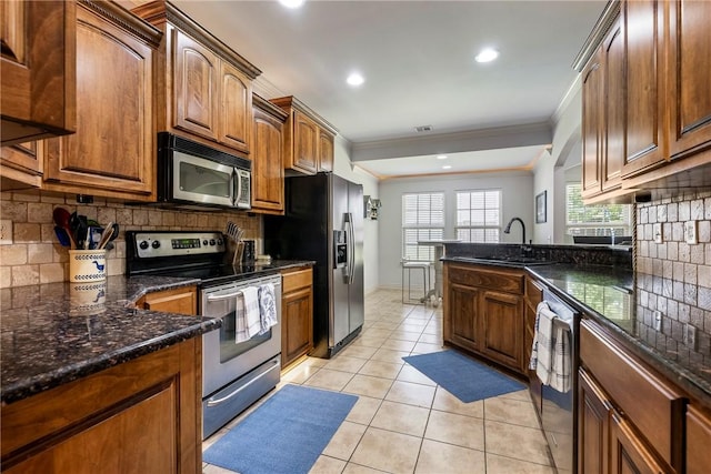 kitchen featuring stainless steel appliances, a sink, ornamental molding, tasteful backsplash, and light tile patterned flooring