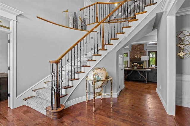 staircase with wood finished floors, a fireplace, and baseboards