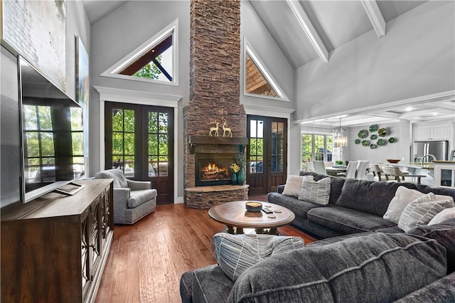 living room with high vaulted ceiling, wood finished floors, beamed ceiling, a fireplace, and plenty of natural light