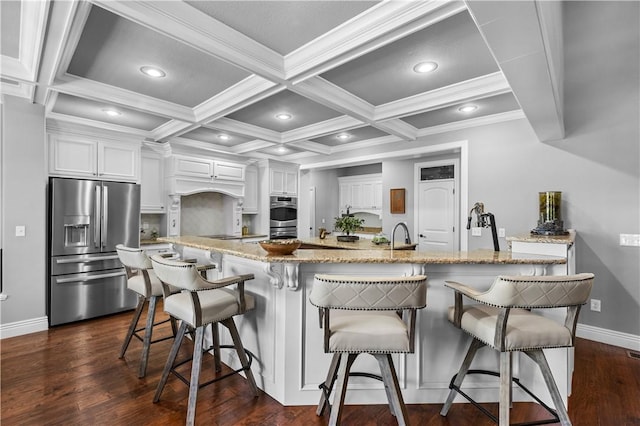 kitchen featuring stainless steel appliances, baseboards, white cabinetry, a breakfast bar, and coffered ceiling