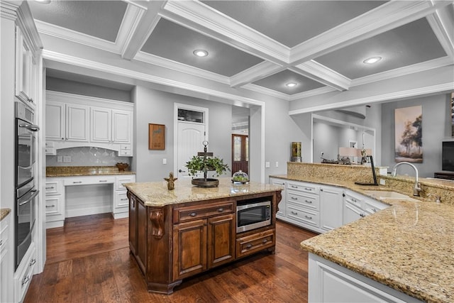 kitchen with a sink, stainless steel appliances, coffered ceiling, a spacious island, and ornamental molding
