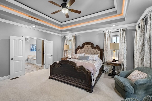 bedroom with a raised ceiling, carpet floors, crown molding, baseboards, and ensuite bathroom