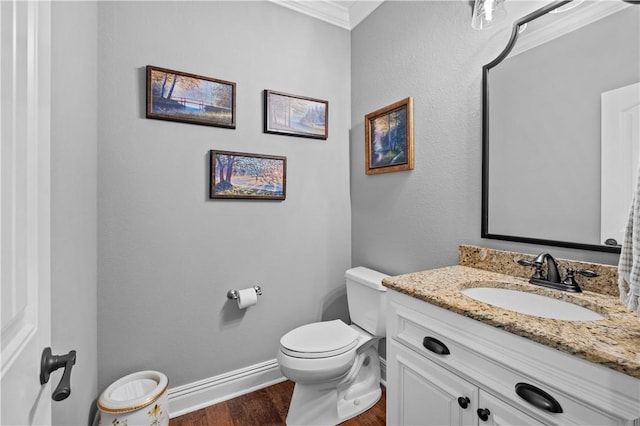 bathroom featuring wood finished floors, crown molding, toilet, vanity, and baseboards