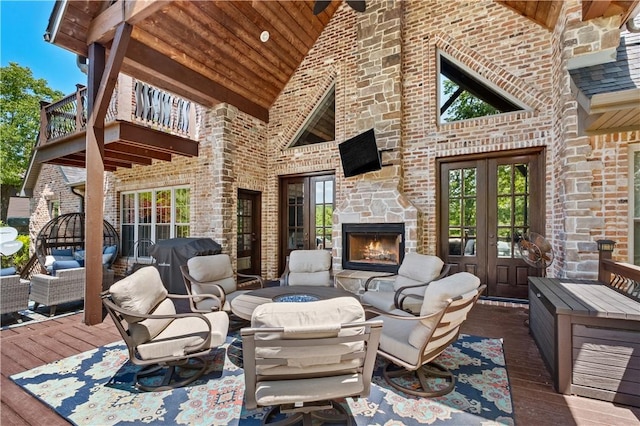 deck featuring french doors, an outdoor living space with a fireplace, and grilling area