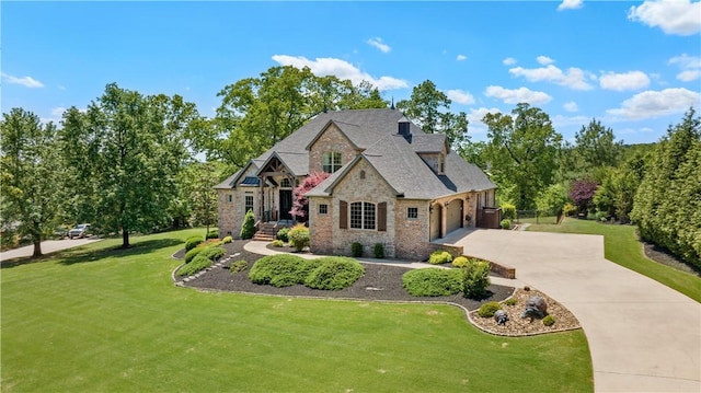 french country inspired facade with brick siding, a front lawn, driveway, and an attached garage