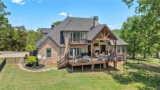 back of property with a balcony, a wooden deck, a chimney, brick siding, and roof with shingles