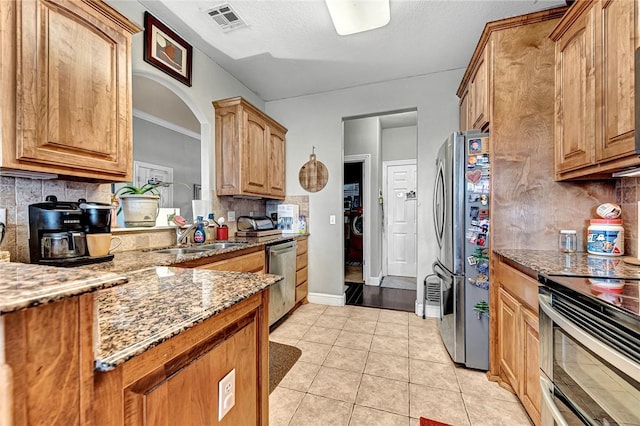 6201 S 36th St, Rogers, AR 72758 - kitchen with stainless steel appliances, a sink, light stone counters, light tile patterned floors, and tasteful backsplash
