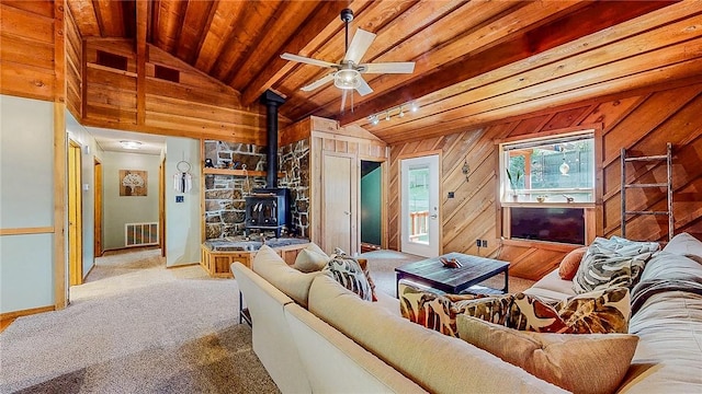 carpeted living room with a wood stove, wood ceiling, ceiling fan, and baseboards