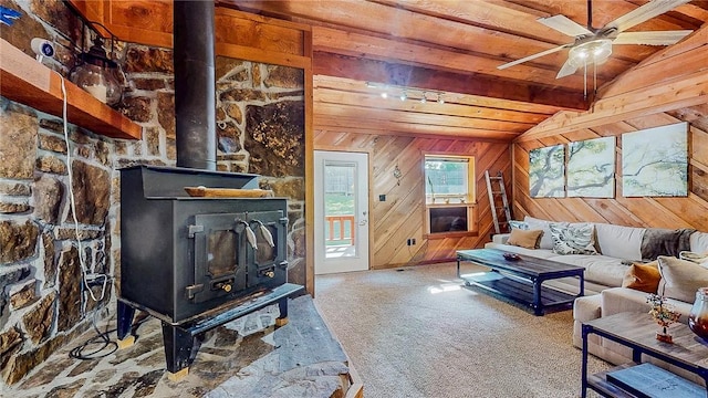 carpeted living room featuring a wood stove, wooden ceiling, wood walls, and a ceiling fan