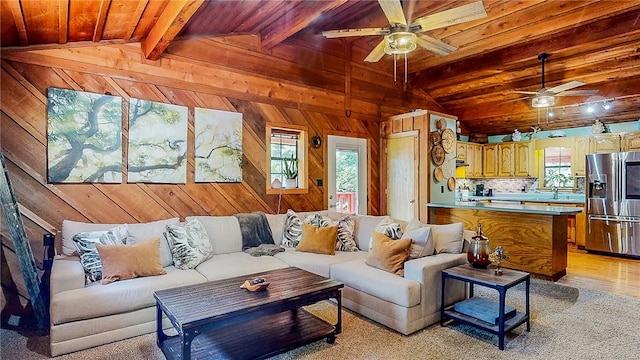 living area with ceiling fan, wood ceiling, wood walls, and light colored carpet